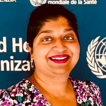 Smiling woman in front of WHO backdrop.