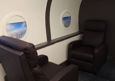 Private jet area with leather brown chairs and windows with sky view