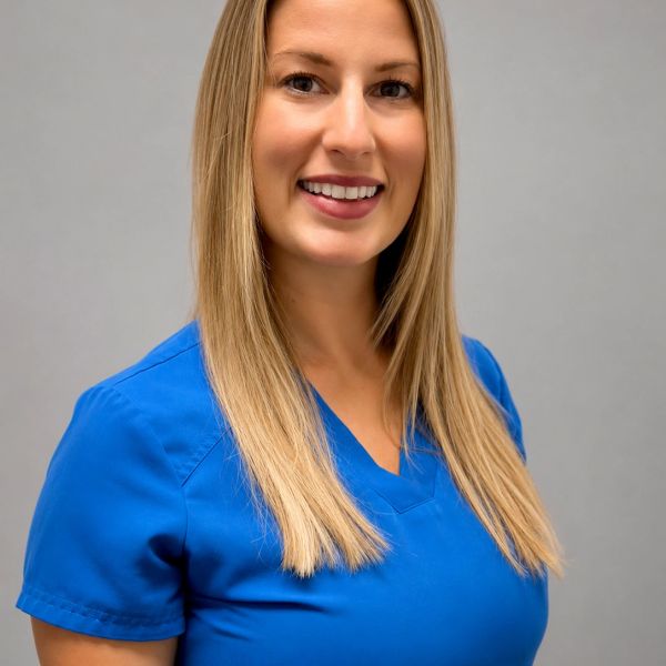 Smiling woman in blue medical scrubs against a plain background.