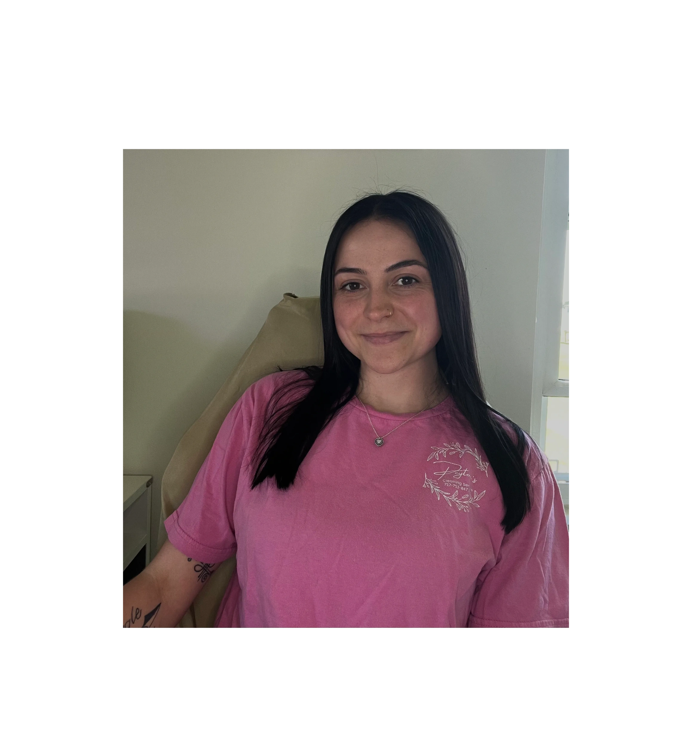 Young woman with long black hair wears a pink shirt and smiles gently.