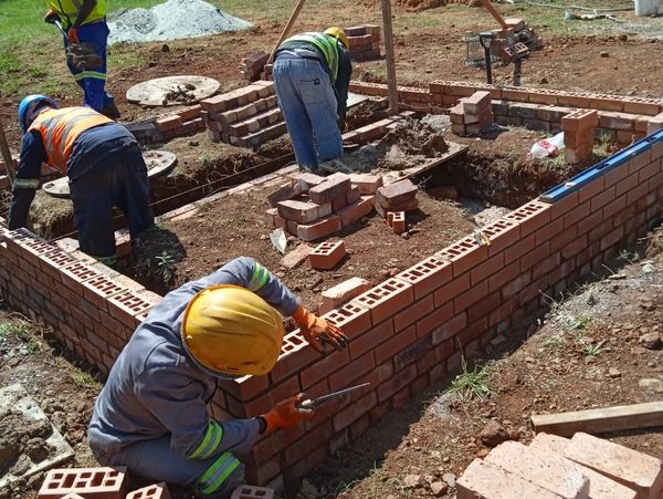 Construction workers laying bricks to build a foundation.