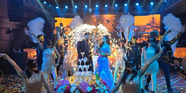 Masked party with sparklers and champagne tower on stage.