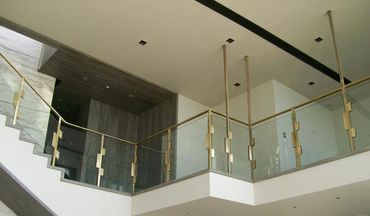 Glass panels with bronze-toned posts and handrails on an interior stair and landing.