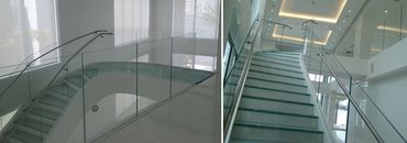 Curved interior stair with glass treads, clear glass balustrades and round metal handrails.