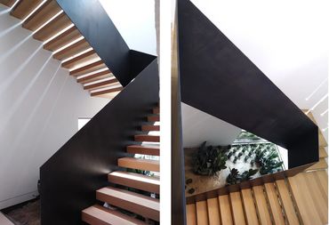 Two views of timber stair treads enclosed by tall, folded black metal panels.