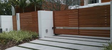 Horizontal-slat gate with a silver-colored band between white piers.