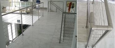 Interior stair and landing railing with round metal posts, horizontal cables and a rounded corner.