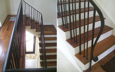 Black decorative balusters and a curved handrail above wood treads and white risers.
