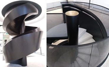 Two views of a dark-metal spiral stair with curved plate enclosure and a glass landing railing.