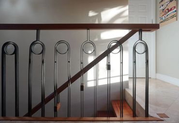 Black balusters with circular details and wood handrails around an interior stair opening.