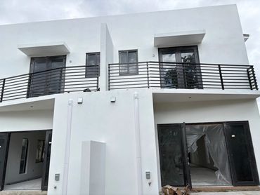 Dark horizontal-bar balcony railings; protective coverings and unfinished interiors below.