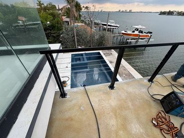 Black posts and cables on a waterfront balcony, with installation equipment still on site.
