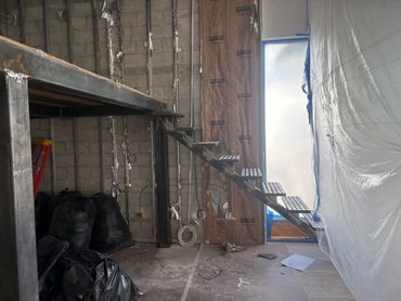 Steel access stair with open metal treads beside a platform during construction.