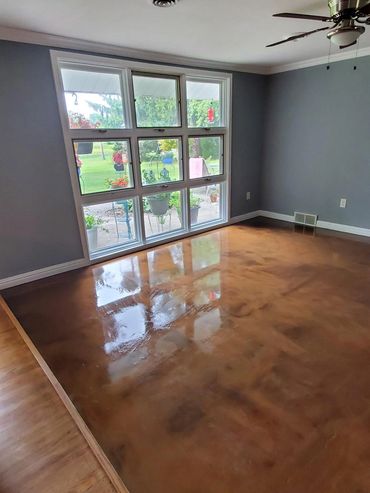Empty room with polished wooden floor and large window overlooking garden.