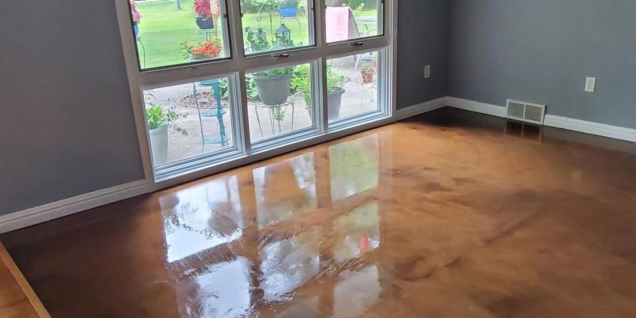 Empty room with polished wooden floor and large window overlooking garden.