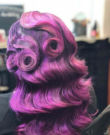 Vibrant purple and pink hair styled in elegant curls and waves.