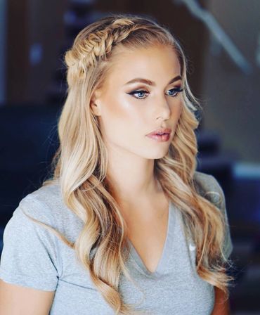 Blonde woman with braided hairstyle and natural makeup in a grey shirt.
