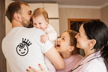 Happy family moment with father holding baby and mother and daughter smiling.