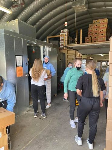 Volunteers move produce into refrigerator