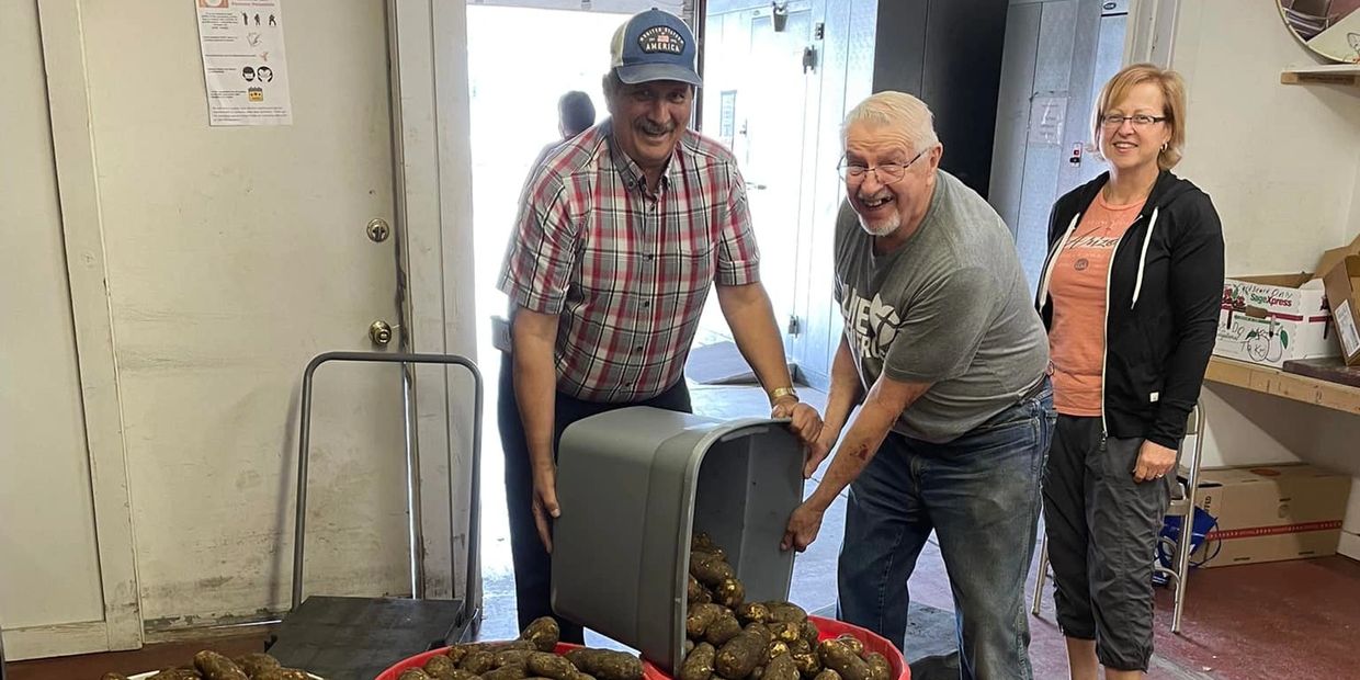 Volunteers move large containers of potatoes 