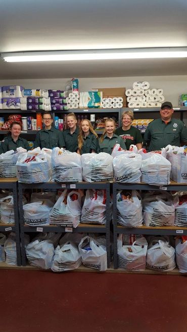 Volunteers stand behind filled grocery bags
