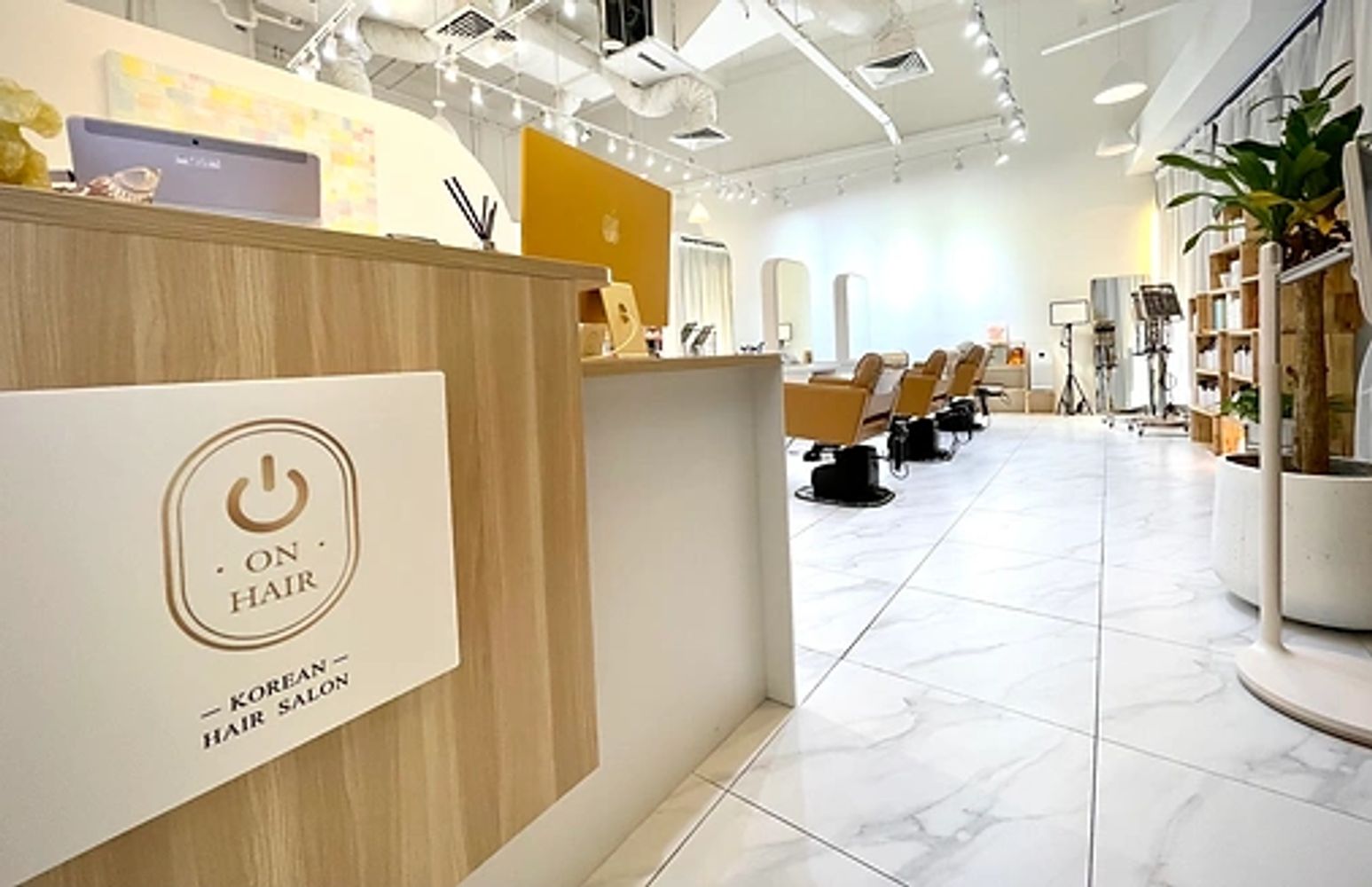 Modern Korean hair salon with stylish chairs and bright lighting.
