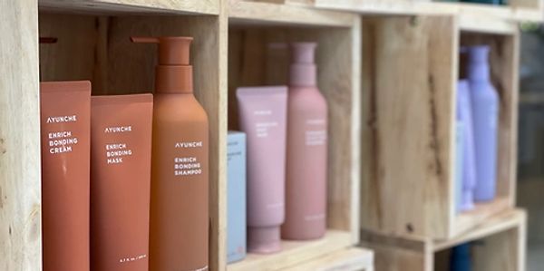 A display of AYUNCHE hair care products on wooden shelves.