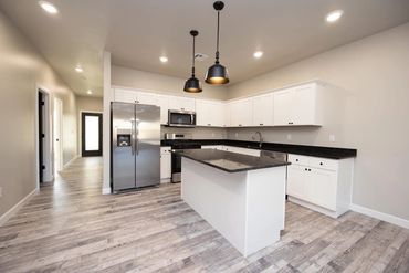 Modern kitchen with white cabinets and black countertops.