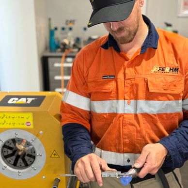 Technician in orange uniform working with CAT industrial equipment.