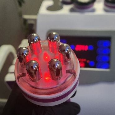 Close-up of a handheld device with metal prongs and red lights.