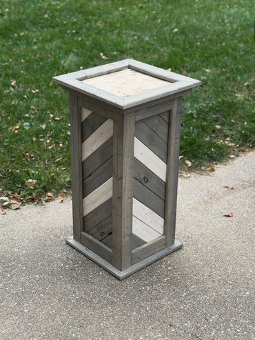 Gray and white chevron taxidermy pedestal base with a rustic wood finish, shown on outdoor pavement.