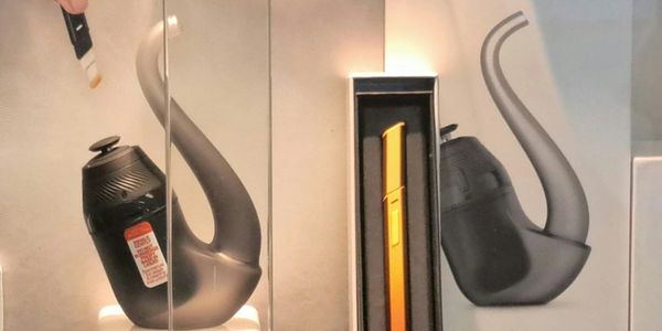 A sleek black and gold electronic pipe displayed in a glass case.