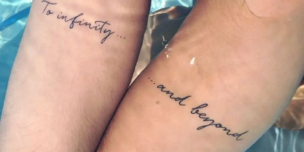 Matching tattoos on two wrists say 'To infinity... and beyond'.