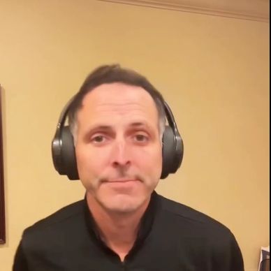 Man wearing large black headphones in a beige room.
