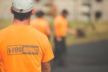 Worker in an orange shirt with 1-800 ASPHALT logo on the back.