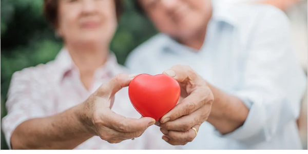 Older couple holding a little plastic heart