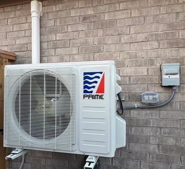 Outdoor air conditioning unit mounted on brick wall.