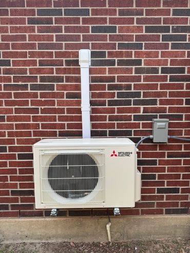 Mitsubishi Electric outdoor air conditioning unit mounted on a brick wall.