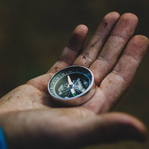 A dirty hand holding a compass.