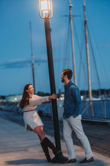 A romantic portrait of a couple sharing an intimate moment under city lights at night by the water