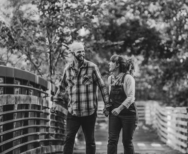 Couple smiling, while holding hands walking across a bride. Stunning black and white photo