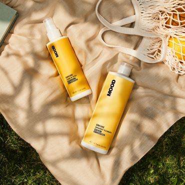 Two yellow MOOD suncare bottles on cloth.