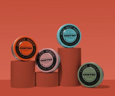 Four Osmo hair styling products on rust-colored pedestals.
