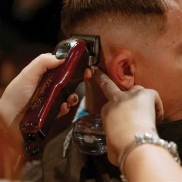 Close-up of a barber cutting a man's hair with clippers.