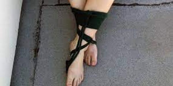 white persons ankles crossed and bound in black rope