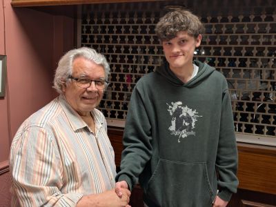 Two men shaking hands indoors, smiling.