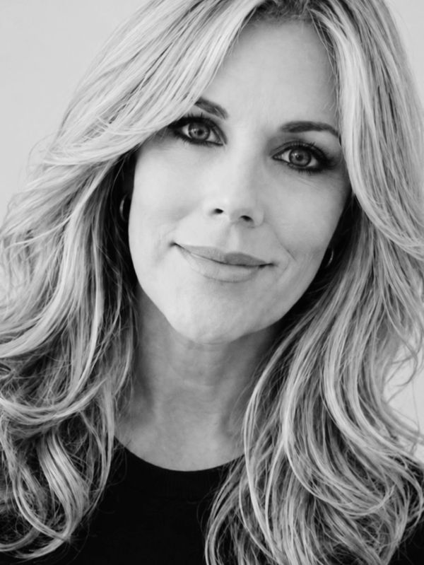 Black and white close-up portrait of a smiling woman with long, wavy hair.