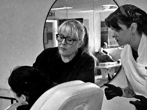 Two women discussing hairstyle with a client in a salon.