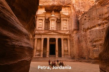 Ancient rock-cut architecture of Petra in Jordan with tourists on camels.