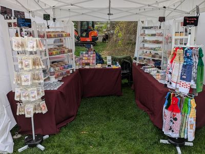 Craft stall with various handmade goods under a white canopy.